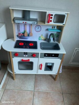 Petite cuisine en bois pour enfants, comprenant des plaques de cuisson, un évier et des accessoires, parfaite pour un jeu éducatif et créatif.