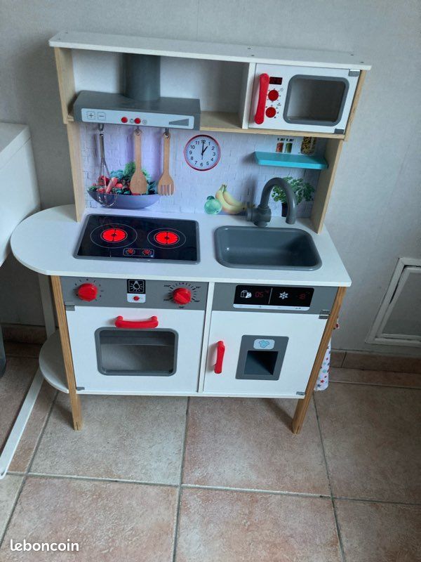 Petite cuisine en bois pour enfants, comprenant des plaques de cuisson, un évier et des accessoires, parfaite pour un jeu éducatif et créatif.